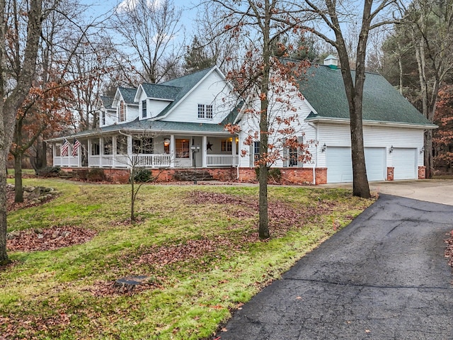 view of front of property with a porch, a garage, and a front lawn