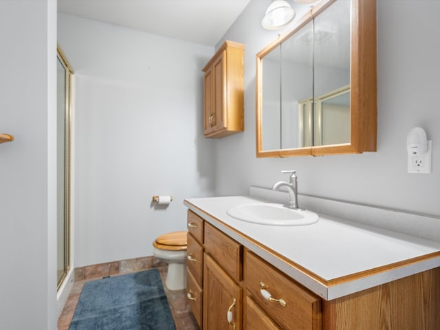 bathroom with tile patterned floors, vanity, toilet, and a shower with door