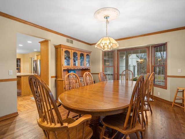 dining area featuring light hardwood / wood-style floors, crown molding, and a notable chandelier