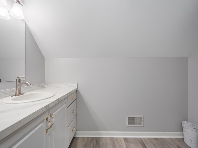 bathroom with hardwood / wood-style flooring, vanity, and lofted ceiling