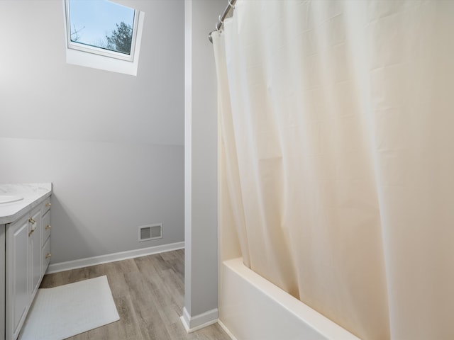 bathroom with shower / bathtub combination with curtain, vaulted ceiling with skylight, vanity, and hardwood / wood-style flooring