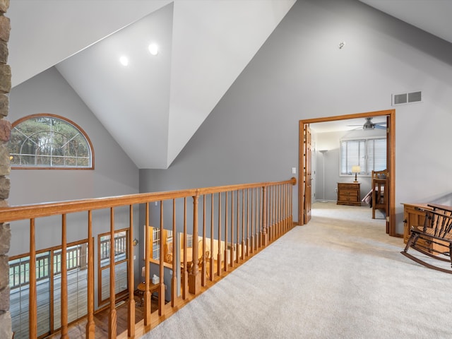 corridor with carpet, plenty of natural light, and vaulted ceiling