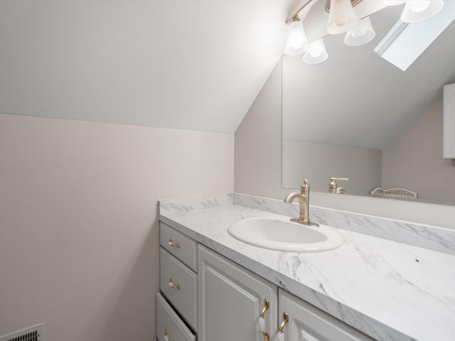 bathroom with vaulted ceiling with skylight and vanity