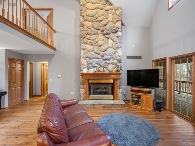 living room with a fireplace, high vaulted ceiling, and hardwood / wood-style flooring