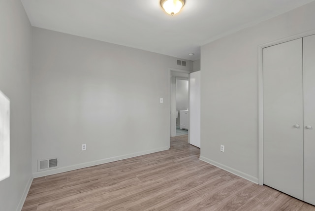 unfurnished bedroom with light wood-type flooring and a closet