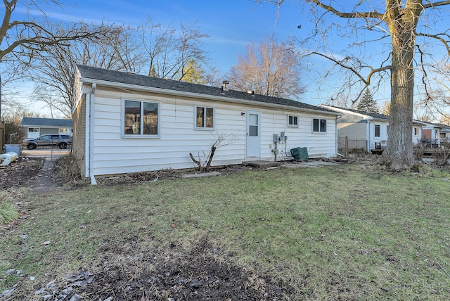 rear view of house with central air condition unit and a lawn