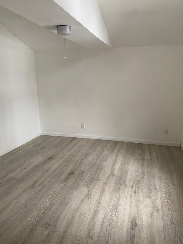 empty room featuring vaulted ceiling and light hardwood / wood-style floors