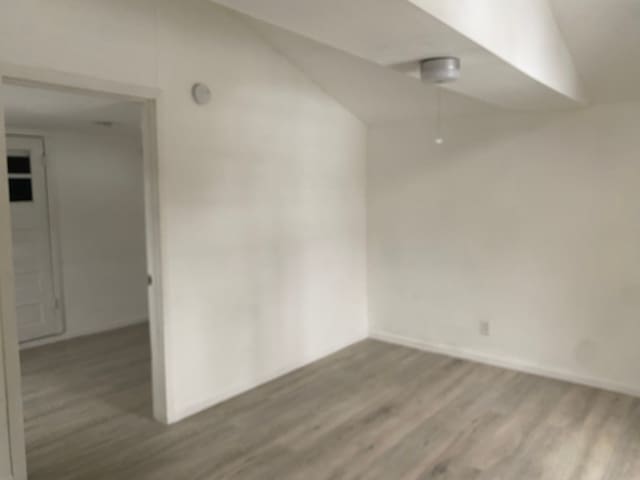 unfurnished room featuring lofted ceiling and wood-type flooring