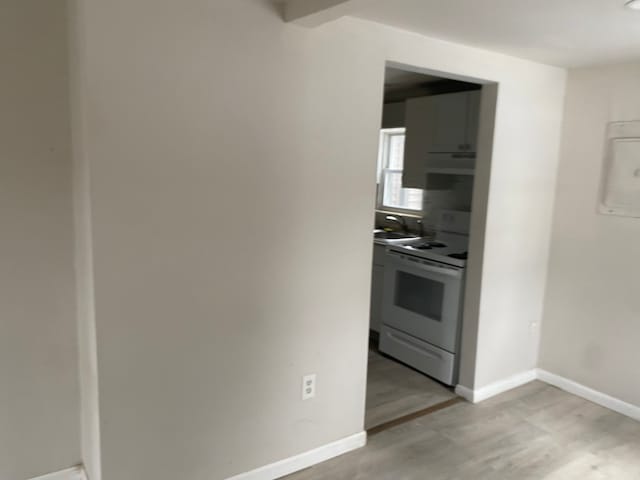 1095 Harding Dr, Grand Blanc, MI 48507 - kitchen featuring white range with electric stovetop, under cabinet range hood, light wood-type flooring, baseboards, and a sink