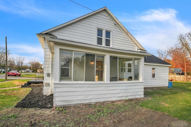 view of property exterior featuring a lawn and a sunroom