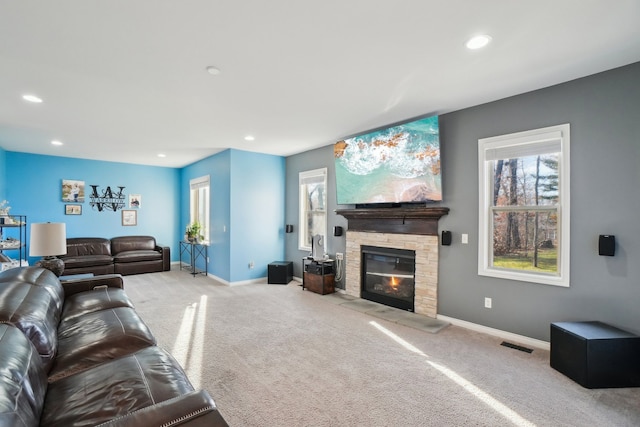 carpeted living room featuring a stone fireplace