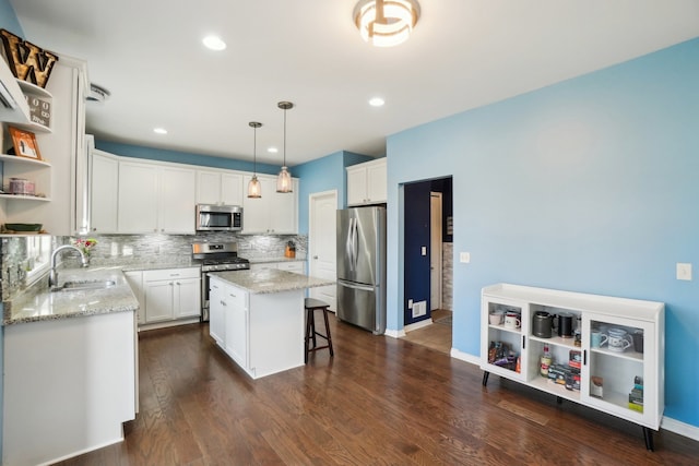 kitchen featuring white cabinetry, sink, hanging light fixtures, a center island, and stainless steel appliances