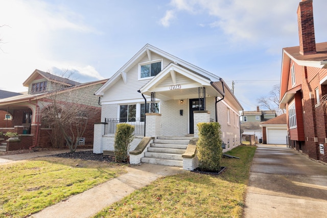 bungalow-style home with a garage, an outdoor structure, a front yard, and a porch