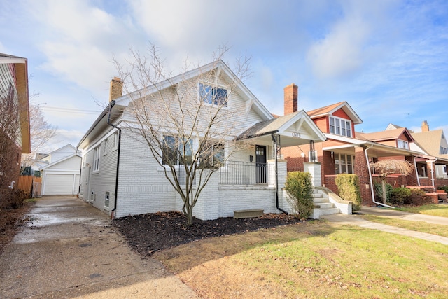 view of front of property featuring a porch, a garage, an outdoor structure, and a front lawn