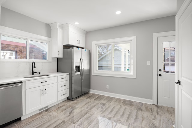 kitchen with sink, decorative backsplash, stainless steel appliances, and white cabinets