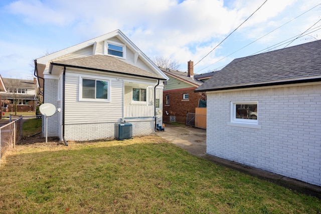 back of property featuring central AC unit and a yard