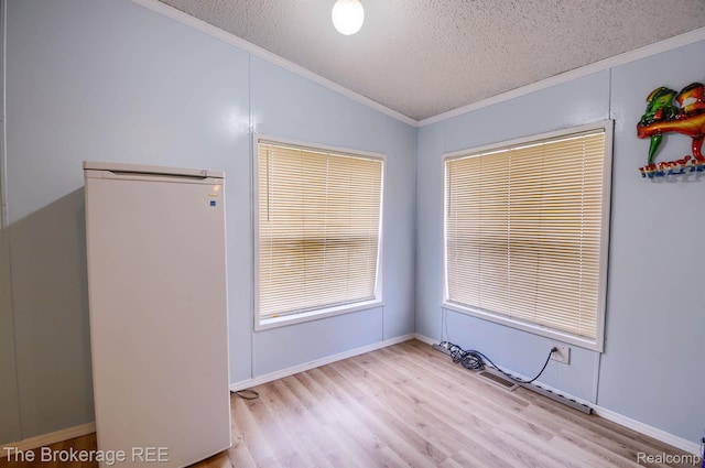 2350 Iowa Ave, Saginaw, MI 48601 - spare room featuring a textured ceiling, vaulted ceiling, ornamental molding, and wood finished floors