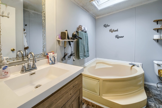 bathroom with lofted ceiling with skylight, a washtub, vanity, and a textured ceiling