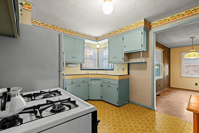 kitchen featuring stainless steel refrigerator, white range with gas cooktop, and backsplash