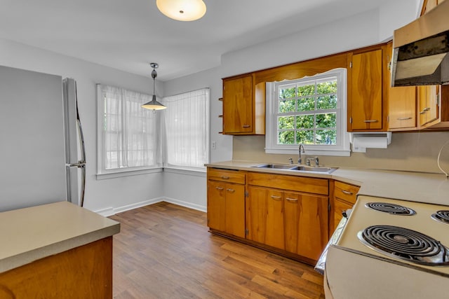 kitchen with ventilation hood, sink, light hardwood / wood-style flooring, stainless steel fridge, and decorative light fixtures