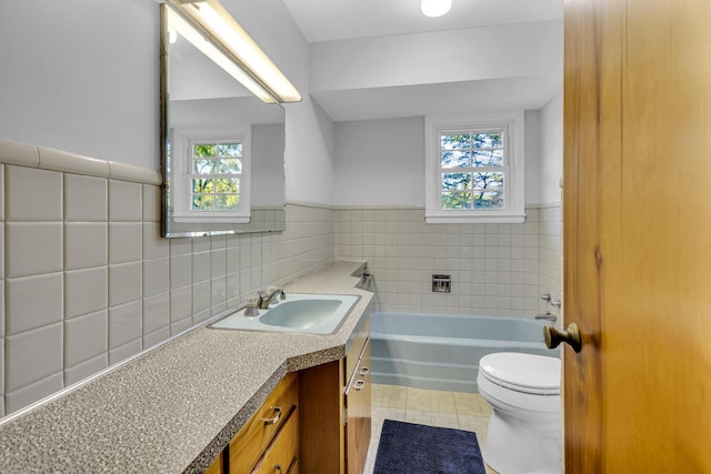 bathroom featuring a wealth of natural light, a bathtub, vanity, and tile walls