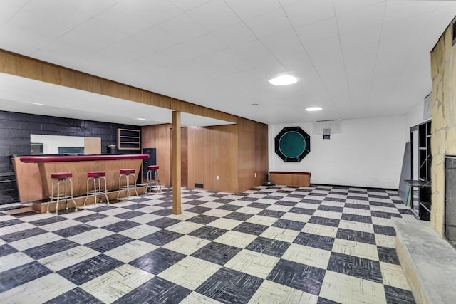 basement featuring bar area and wood walls