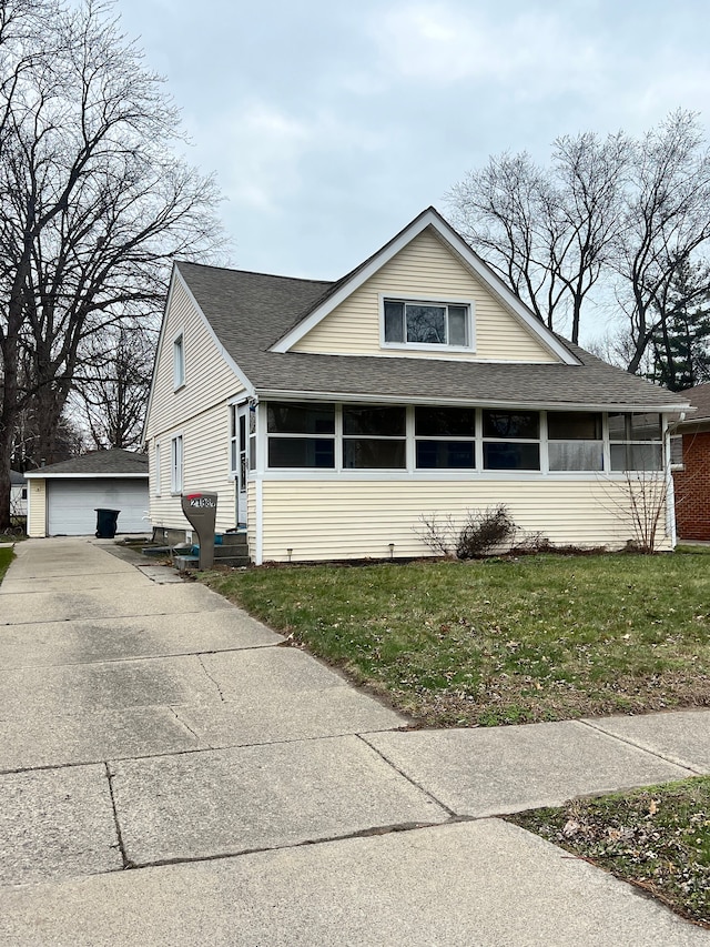 view of front of house featuring a sunroom, a garage, an outdoor structure, and a front yard