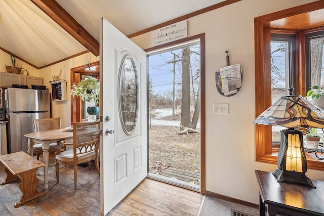 entrance foyer with lofted ceiling with beams, light hardwood / wood-style floors, and a wealth of natural light