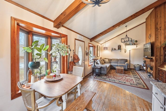 dining room featuring lofted ceiling with beams, light hardwood / wood-style flooring, and a healthy amount of sunlight