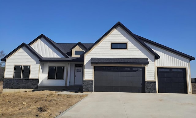 modern farmhouse style home featuring board and batten siding, stone siding, concrete driveway, and a garage