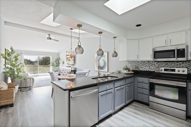 kitchen with gray cabinetry, backsplash, hanging light fixtures, kitchen peninsula, and stainless steel appliances