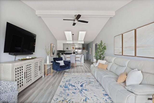 living room featuring lofted ceiling with skylight, ceiling fan, and light hardwood / wood-style floors