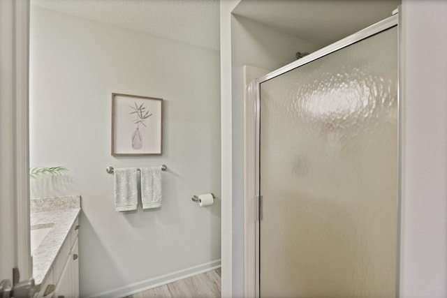 bathroom featuring hardwood / wood-style floors, vanity, an enclosed shower, and a textured ceiling