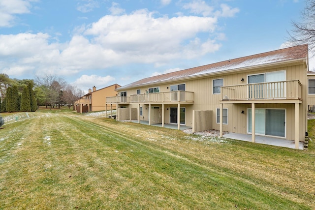 rear view of house with a lawn, a balcony, and a patio