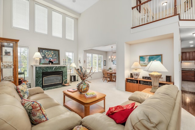 living room featuring a towering ceiling, a fireplace, and an inviting chandelier