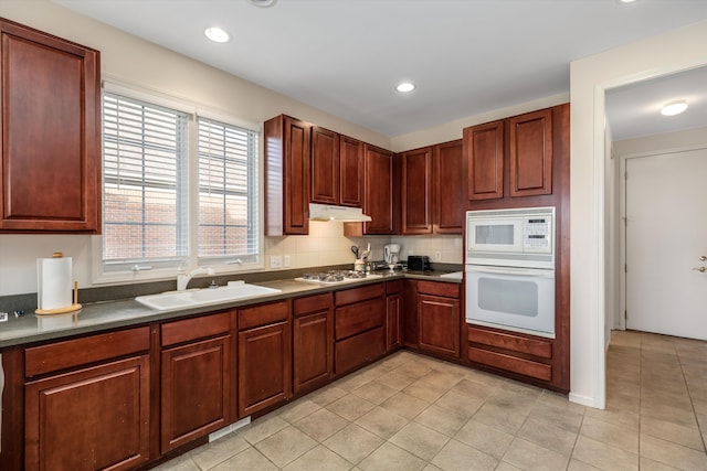 kitchen with light tile patterned flooring, white appliances, backsplash, and sink