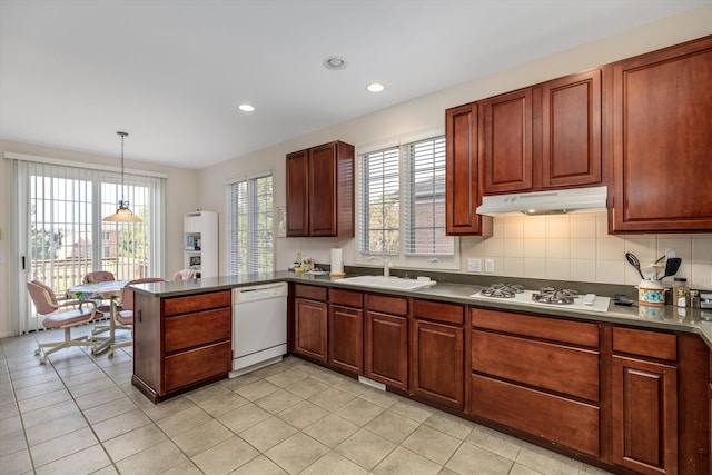 kitchen featuring kitchen peninsula, a wealth of natural light, white appliances, sink, and pendant lighting