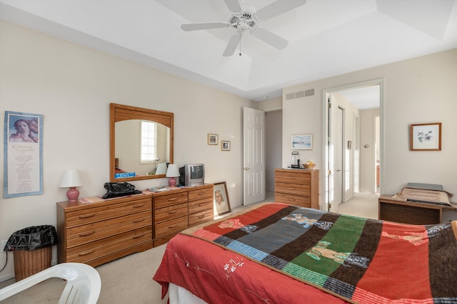 carpeted bedroom with a raised ceiling and ceiling fan