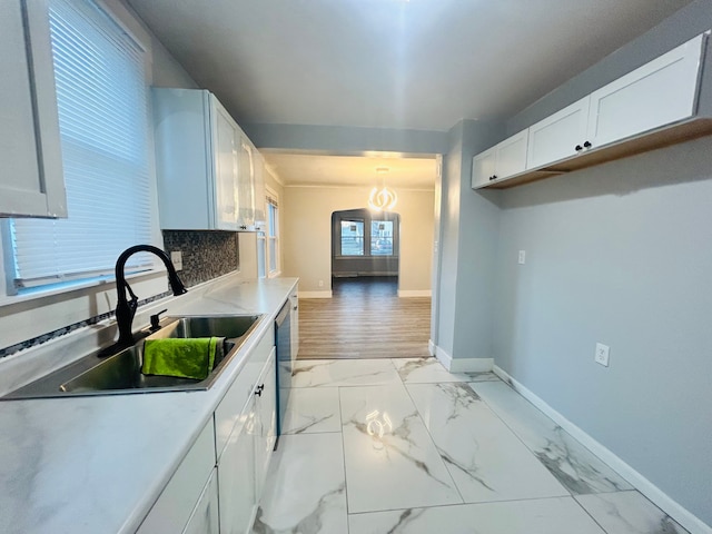 kitchen with white cabinetry, backsplash, hanging light fixtures, and sink