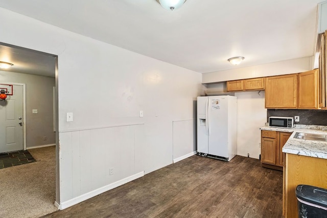 kitchen with white refrigerator with ice dispenser, dark colored carpet, tasteful backsplash, and sink