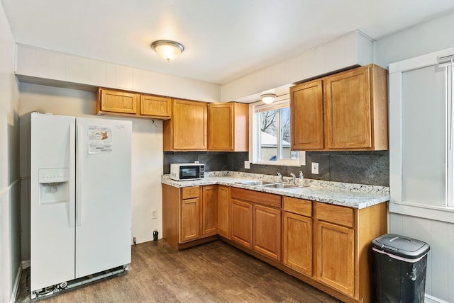 kitchen with dark hardwood / wood-style floors, white appliances, sink, and tasteful backsplash