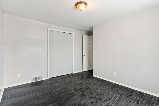 unfurnished bedroom featuring a closet and dark wood-type flooring