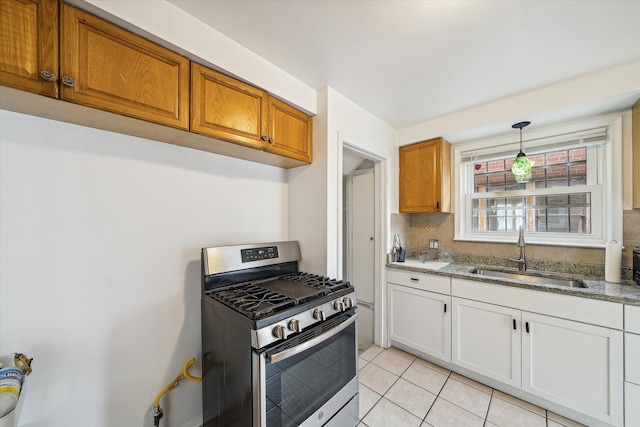 kitchen with gas range, sink, light tile patterned flooring, pendant lighting, and white cabinets