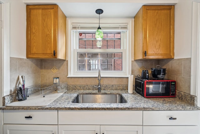 kitchen featuring light stone countertops, sink, hanging light fixtures, and tasteful backsplash