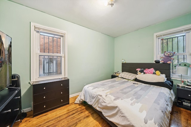 bedroom with multiple windows and hardwood / wood-style flooring