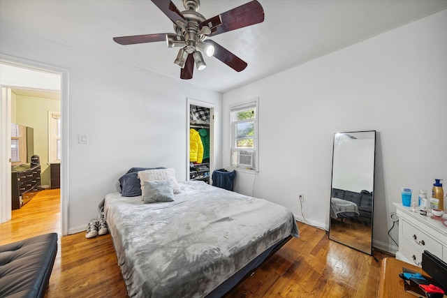 bedroom featuring ceiling fan, cooling unit, and wood-type flooring