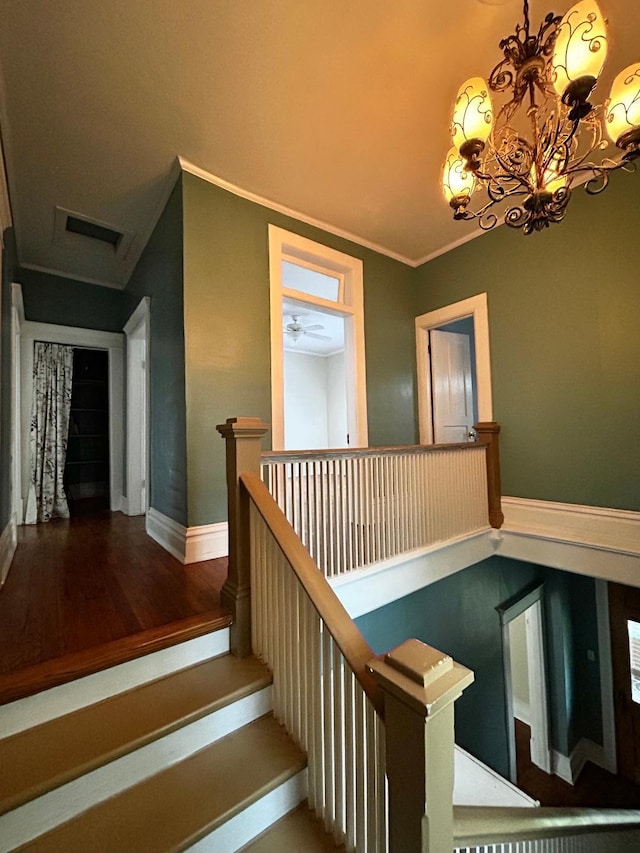 staircase with baseboards, an inviting chandelier, visible vents, crown molding, and wood finished floors