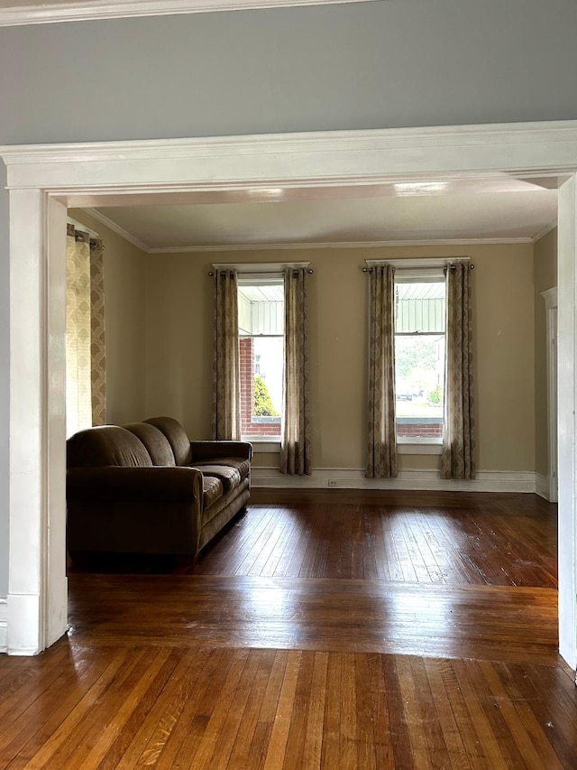 living area featuring ornamental molding, wood-type flooring, baseboards, and a healthy amount of sunlight