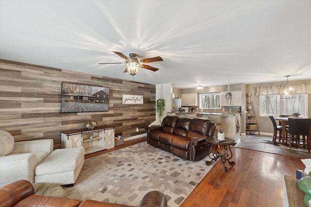 living room featuring wooden walls, dark hardwood / wood-style flooring, and ceiling fan with notable chandelier