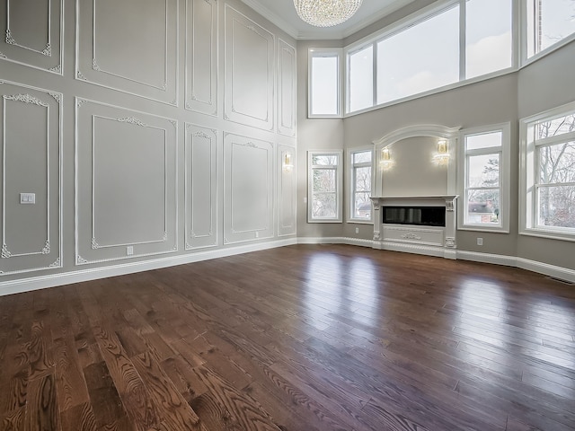 unfurnished living room with dark hardwood / wood-style flooring, crown molding, and a healthy amount of sunlight